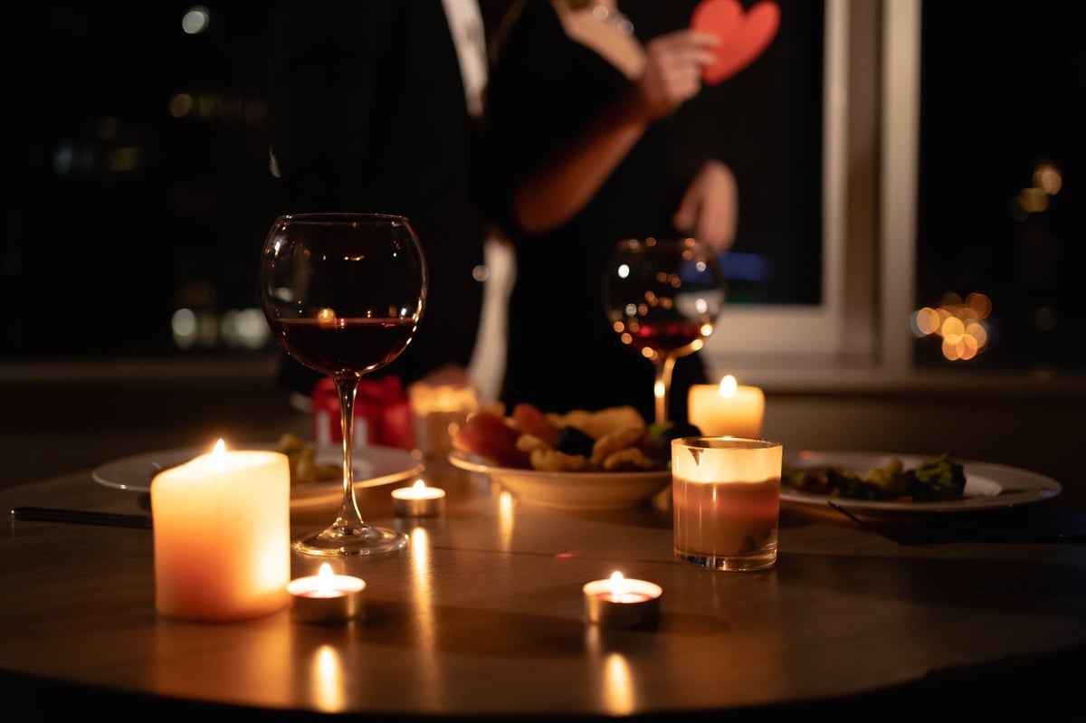 romantic dinner setting, red wine in glasses and candles, date for two, Valentine's Day evening, burning candles on the table, close-up