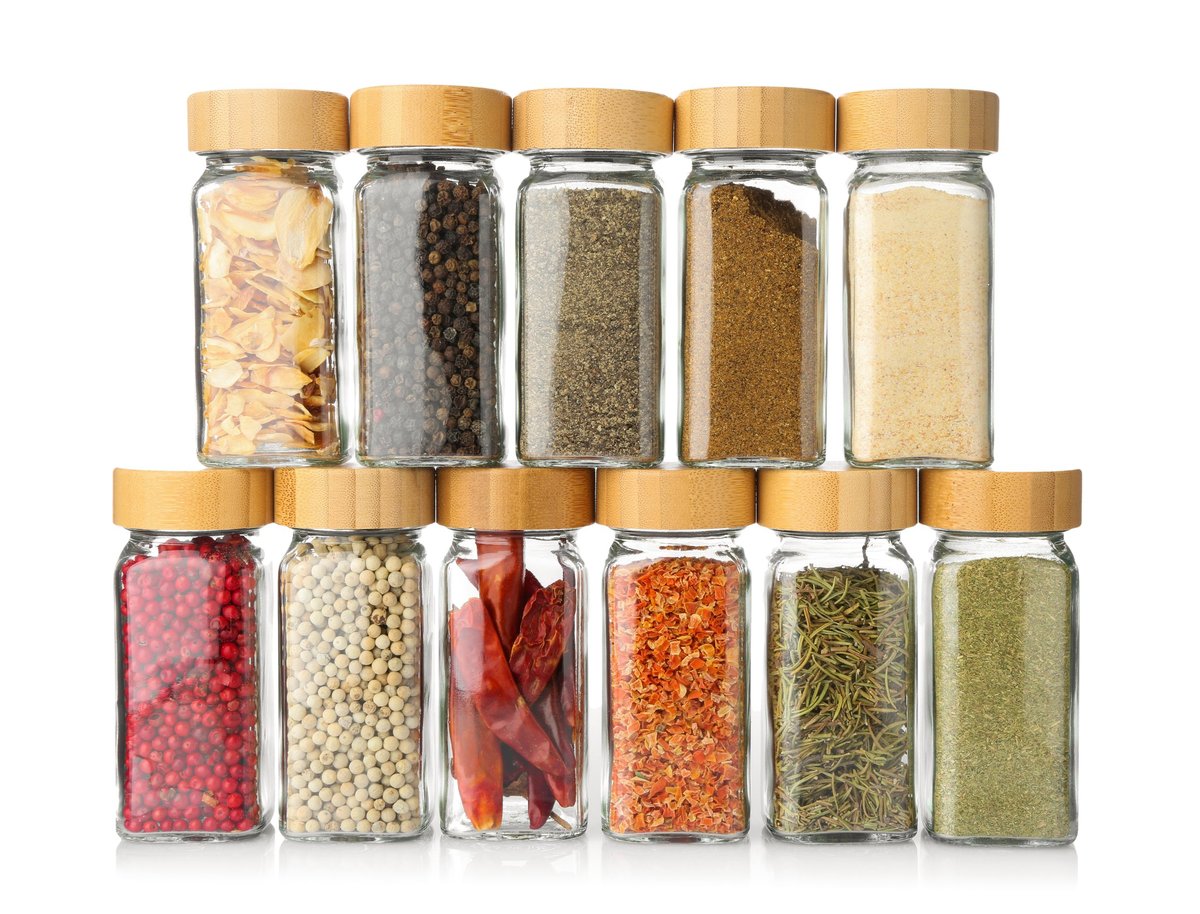 Different aromatic spices in glass jars isolated on white