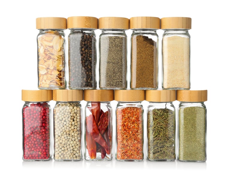 Different aromatic spices in glass jars isolated on white