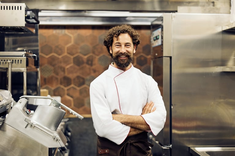 Chef smiling in restaurant kitchen wearing white uniform