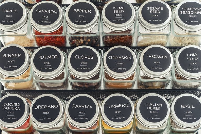 Assorted spices in glass jars with metal lids on a black metal shelf, closeup
