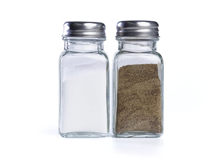 Glass salt and pepper shakers with metal caps isolated on white background