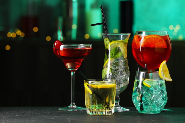 Glasses of tasty cocktails on dark table against blurred background
