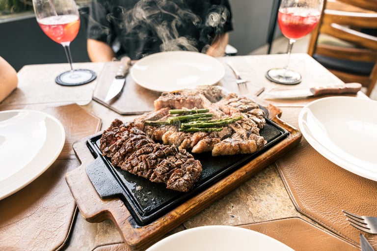 Platter of steaming grilled steak with asparagus serving as the centerpiece on a textured restaurant table