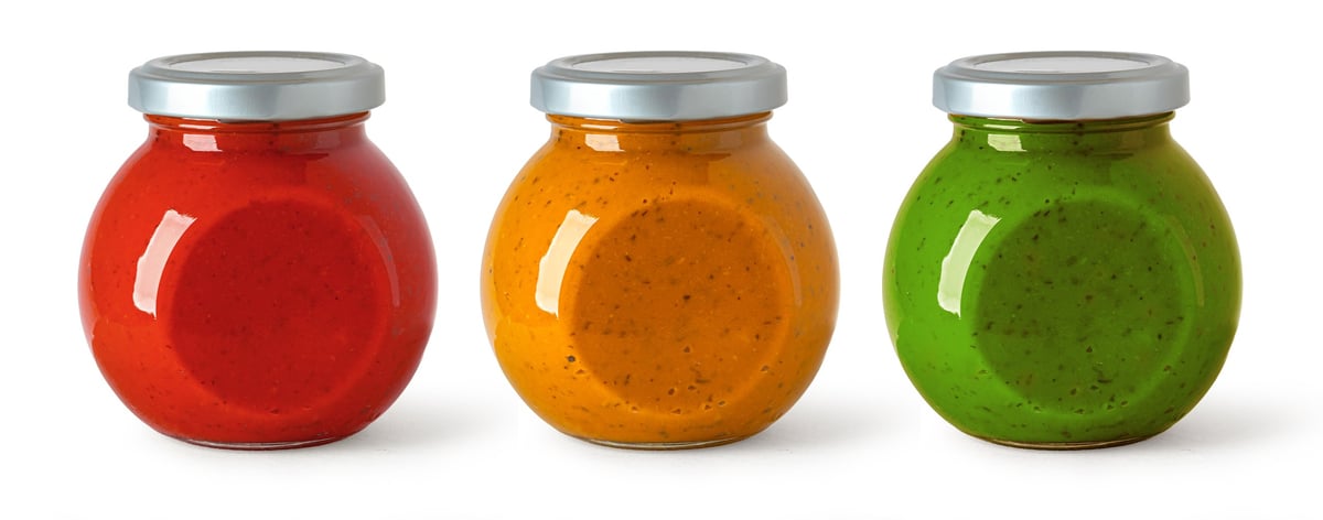 Collection of three glass jars filled with colorful food sauces and condiments